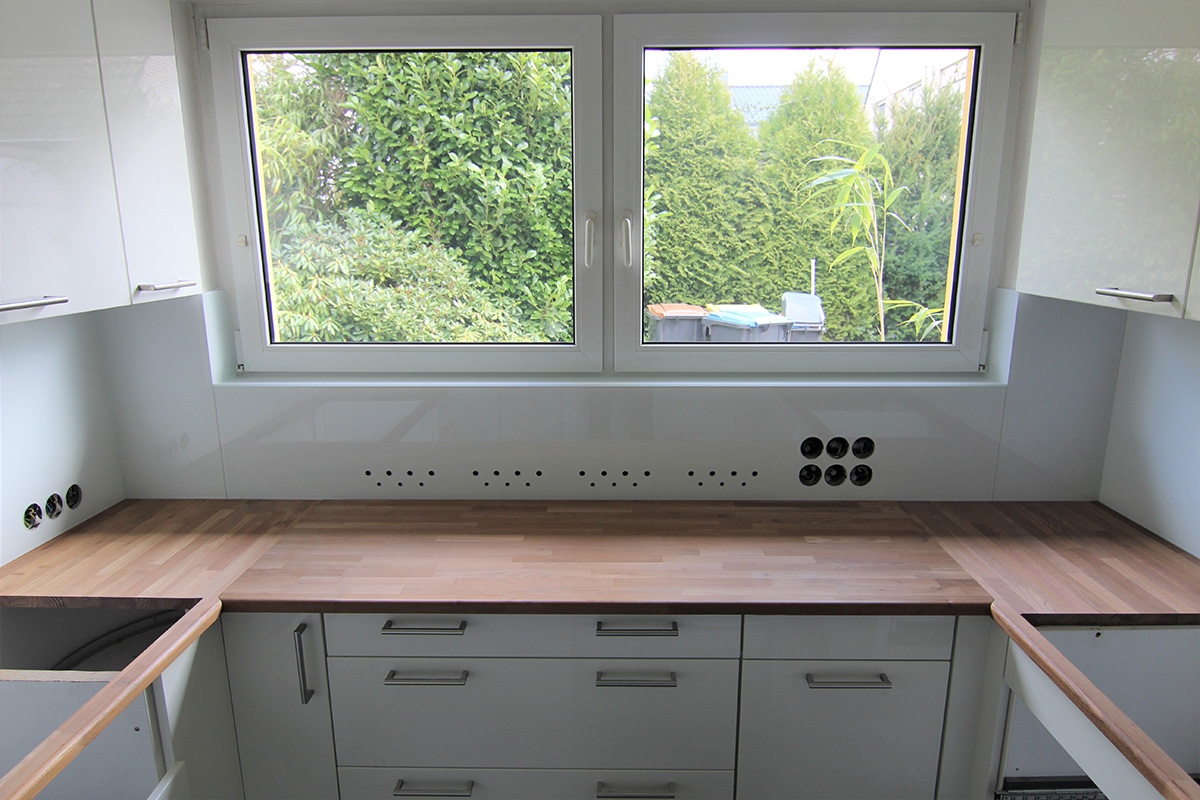Küche mit Glasrückwand unter dem Fenster